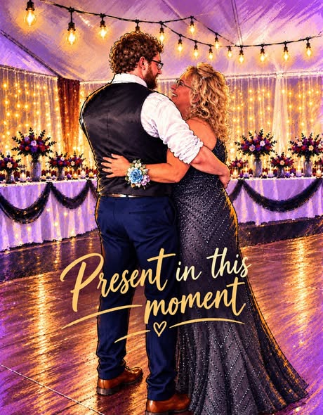 A couple dancing together in a beautifully decorated venue with twinkling lights and elegant table settings. The woman is wearing a shimmering gown, and the man is in a formal outfit with a vest. The text overlay reads 'Present in this moment.'
