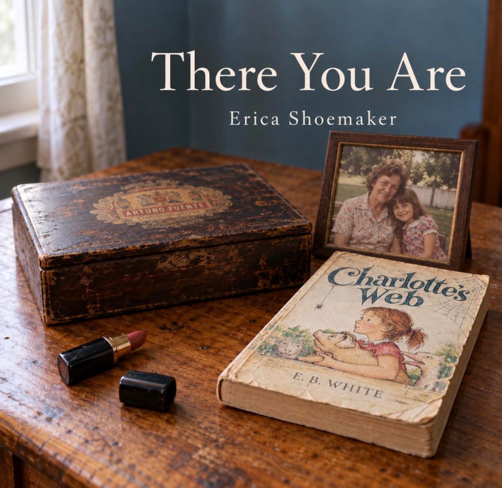 An antique wooden box labeled 'Arturo Fuente,' a vintage copy of 'Charlotte's Web' by E.B. White, a red lipstick tube, and a framed photo of an older woman with a young girl on a wooden table.